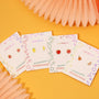 The Orange Enamel Flat Back Kids Earrings, hypoallergenic and perfect for sensitive ears, are shown on JaxKelly-branded cards with a bright orange backdrop and soft pink decorative accents.