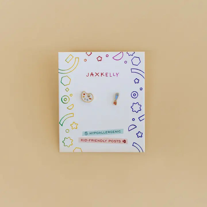 The Artist Palette Enamel Flat Back Kids Earrings, shaped like a palette and brush, are displayed on a JaxKelly card with colorful doodles and "Hypoallergenic" and "Kid-Friendly Posts" labels—ideal for sensitive ears.