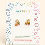 A pair of JaxKelly Roller Skate Enamel Flat Back Kids Earrings, featuring rainbow details, are shown on a white card decorated with colorful geometric and star motifs. The packaging is labeled “JaxKelly,” “Hypoallergenic,” and “Kid-Friendly Posts.” Crafted with surgical-grade stainless steel, these kids earrings offer safe and hypoallergenic wear.