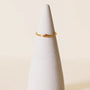The Half Moon Champagne CZ Ring, a delicate gold plated stacking ring featuring a small champagne cubic zirconia, is displayed on a white cone-shaped stand against a plain light background.