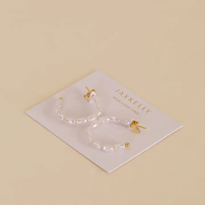 A pair of JaxKelly Multi Pearl Hoop Earrings with gold plating and freshwater pearl beads, shown on a white JaxKelly card against a light beige background.