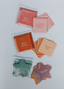 A top-down view of Positivity Shower Affirmations™ card sets, including square and star-shaped cards with uplifting messages like "Self Love Shower Affirmations" and "I can be anything I want to be.