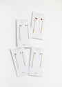 Four pairs of JaxKelly Studded Threader - Fire Opal earrings, each with 18K gold plating and gemstone studs in blue, white, red, or clear, are displayed on “OPAL” cards in a flat lay on a white background.