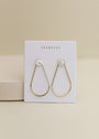 A Gold Long Oval Hoop, ideal for daily wear, shown on a white JaxKelly card with a beige background.