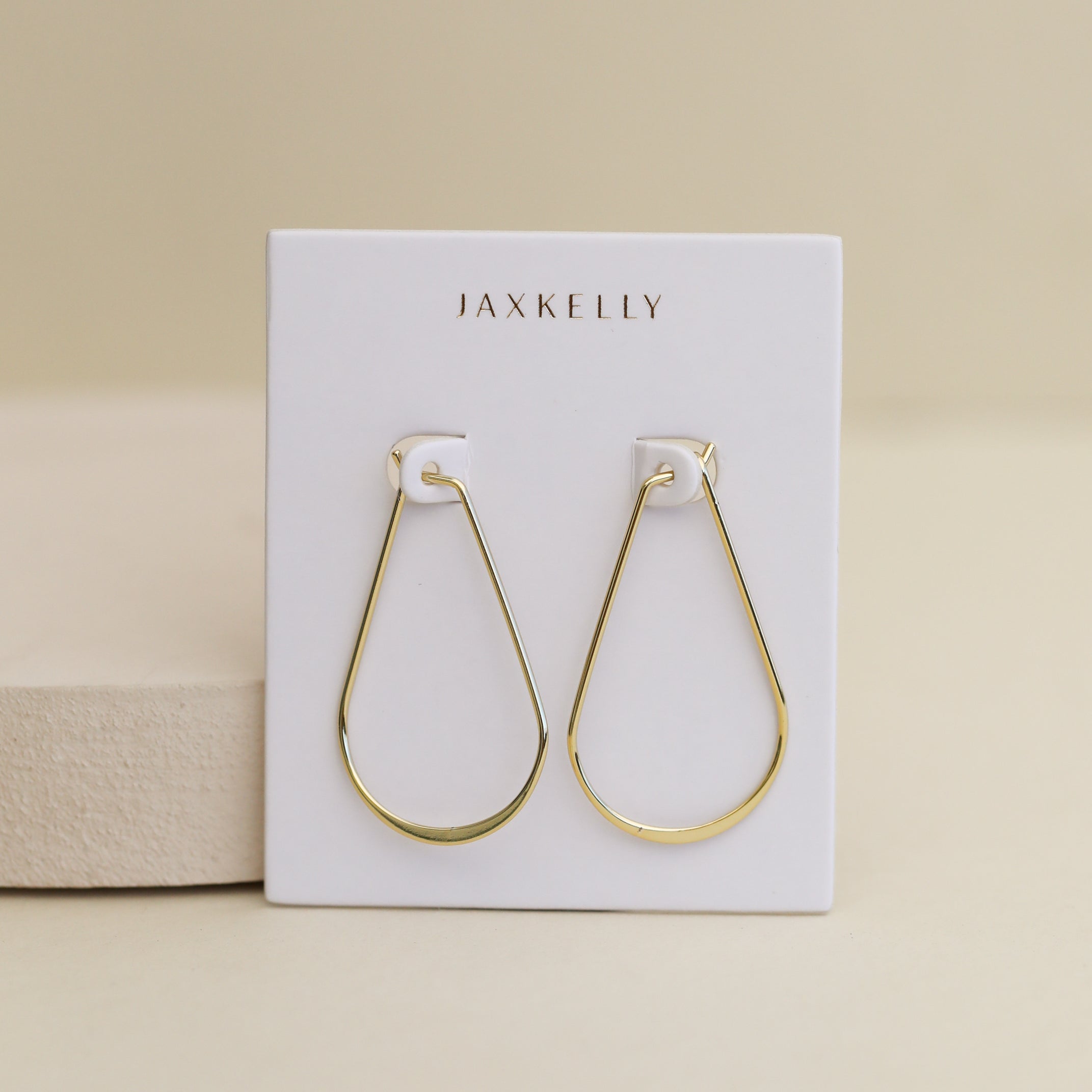 A Gold Long Oval Hoop, ideal for daily wear, shown on a white JaxKelly card with a beige background.