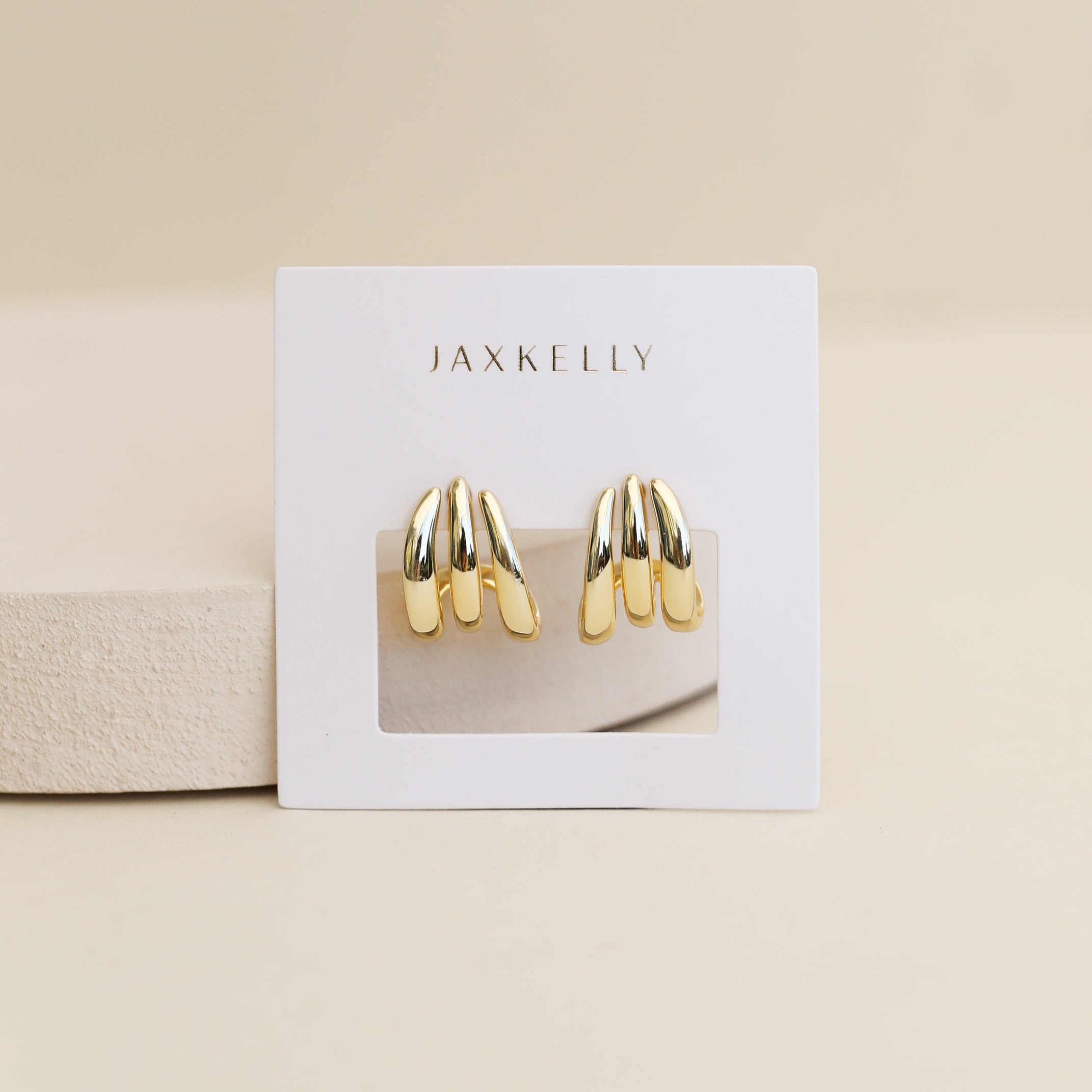 Gold hoop earrings on JaxKelly display card against neutral background