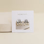 The Silver Three Hoop Huggie earrings feature a modern, layered sterling silver design displayed on a white JaxKelly card—perfect minimalist accessories to elevate any look.