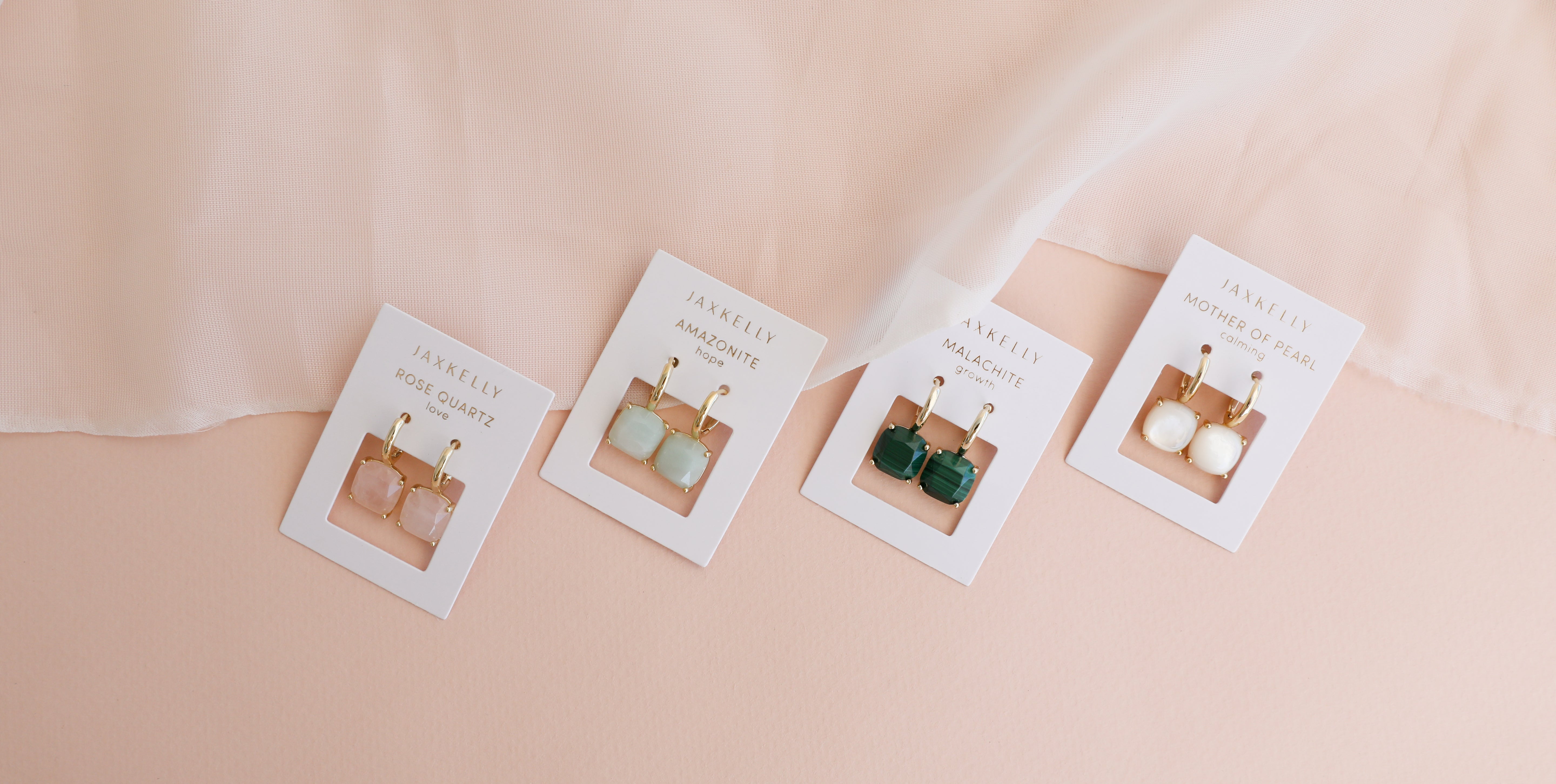 Gold gemstone hoop earrings on display cards in soft neutral setting