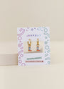 Boot Enamel Charm Hoop earrings feature colorful cowboy boot charms and come on a playful JaxKelly card. Hypoallergenic and kid-friendly, they're perfect for sensitive ears, with fun geometric designs on the packaging.