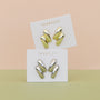 A pair of Silver Double Bold Bar earrings displayed on white JaxKelly cards, set against a pastel peach and green background.