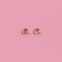 The Bunny Enamel Flat Back Kids Earrings are gold and white bunny-shaped studs, made from surgical-grade stainless steel for sensitive ears, shown on a solid pink background.