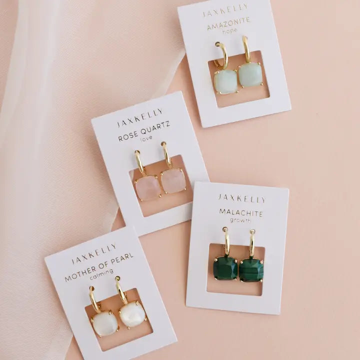 The JaxKelly Gemstone Mini Drop collection includes Rose Quartz (pink, love), Amazonite (green-blue, hope), Mother of Pearl (white, calming), and Malachite (green, growth) earrings—all elegant, gold plated, and tarnish-free.