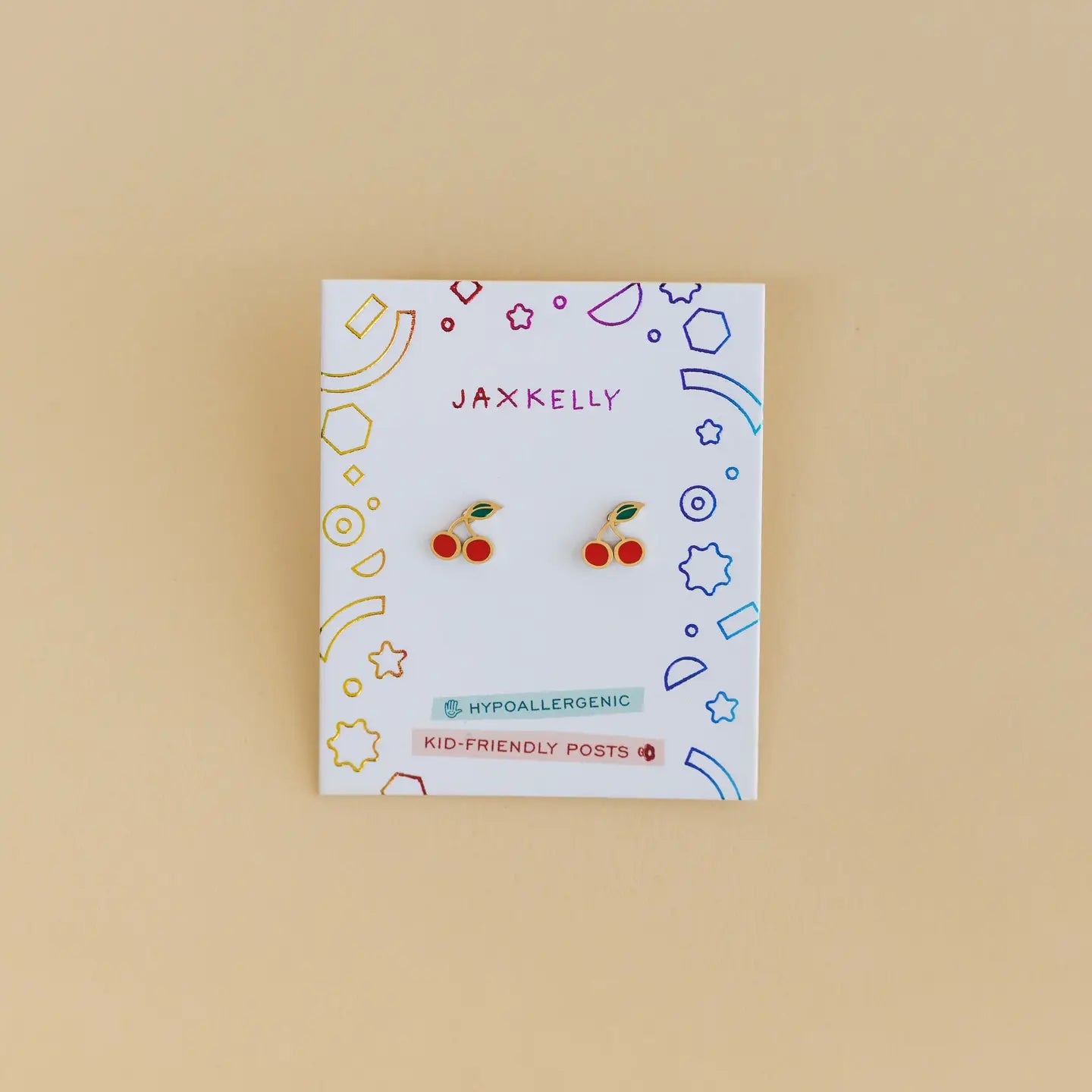 Cherry Enamel Flat Back Kids Earrings displayed on a decorative JaxKelly card labeled "Hypoallergenic and Kid-Friendly Posts," perfect for sensitive ears, shown against a plain beige background.