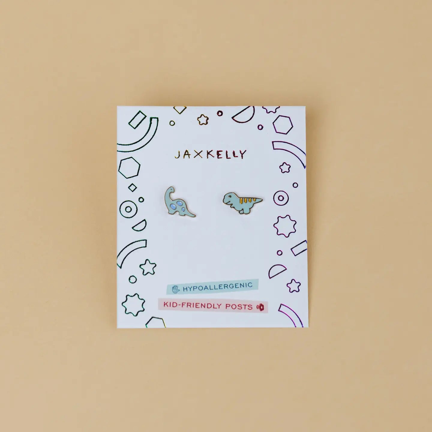 The Dinosaur Enamel Flat Back Kids Earrings feature blue and green dinosaur designs on a Jax Kelly card. The playful beige card notes "Hypoallergenic Earrings" and "Kid-Friendly Posts," making them ideal for sensitive ears.