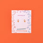 The Ice Cream Enamel Flat Back Kids Earrings are displayed on a colorful JaxKelly card labeled Hypoallergenic and Kid-Friendly Posts, set against an orange background. Perfect for playful style and sensitive ears.