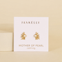 JaxKelly’s Sun Ray - Mother of Pearl stud earrings, featuring a pearl center, are displayed on a white card reading “Mother of Pearl” and “calming.” These elegant, hypoallergenic earrings combine gold sun ray design with gentle sophistication.