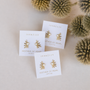Three pairs of JaxKelly Sun Ray - Mother of Pearl stud earrings are shown on white cards, surrounded by dried thistle flowers against a light backdrop.