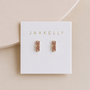 A pair of JaxKelly Rose Gold Bar Druzy stud earrings with pink gemstones, hypoallergenic and displayed on a white JaxKelly-branded card against a soft beige background.