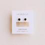 JaxKelly Obsidian Huggie earrings: dainty gold huggies with round black obsidian stones, displayed on a white card labeled "Obsidian - black negativity.
