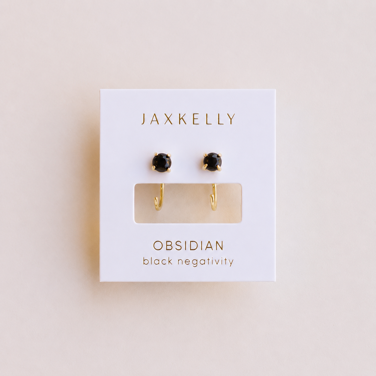 JaxKelly Obsidian Huggie earrings: dainty gold huggies with round black obsidian stones, displayed on a white card labeled "Obsidian - black negativity.