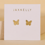 A pair of gold-plated Butterfly stud earrings by JaxKelly with sterling silver posts, shown on a white card with the JaxKelly logo. A soft beige background highlights this elegant jewelry.