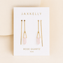 A pair of JaxKelly Gemstone Threader - Rose Quartz earrings with gold chains and rose quartz pendants, displayed on a white love card against a soft beige background.