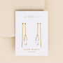 JaxKelly Gemstone Threader - Clear Quartz earrings, ideal for minimalist jewelry lovers, feature clear quartz pendants on gold chain threaders. Displayed on a white card labeled "Clear Quartz – cleansing," set against a beige background.