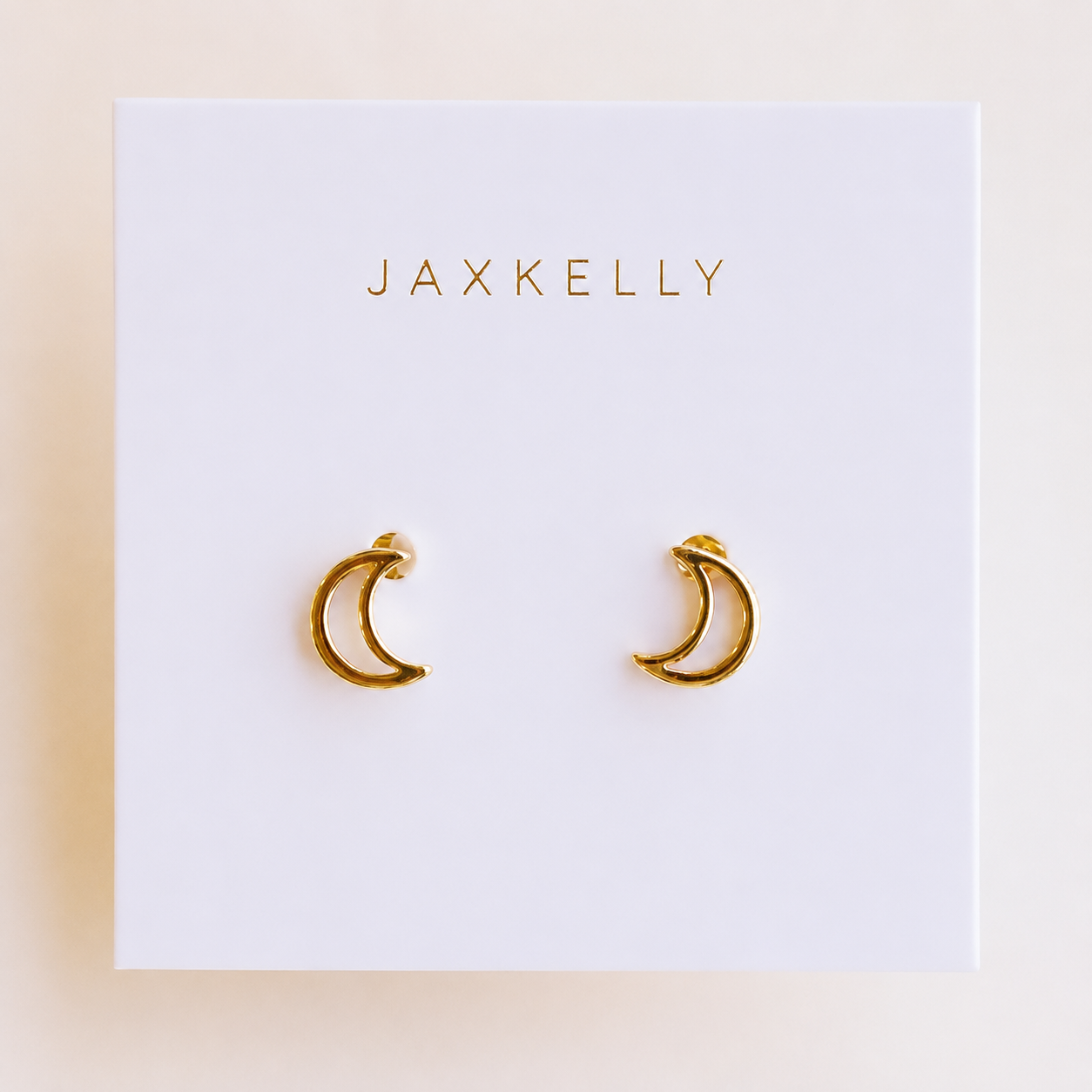 A pair of Minimalist Moon small 18k gold plated hollow moon earrings displayed on a white card with the JaxKelly brand name printed in gold at the top.