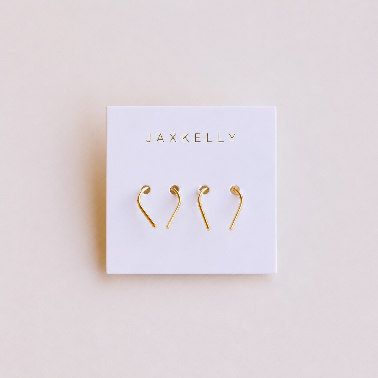 A white card with JaxKelly in gold showcases two pairs of Minimalist Horseshoe gold plated earrings—ideal for everyday wear—against a light beige background.