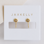 JaxKelly Sun Huggie gold-plated hoop earrings with a central clear gemstone, displayed on a white card labeled "JaxKelly" in gold above a rectangular cutout.