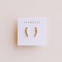 The JaxKelly Champagne Crawler gold hoop earrings with star-shaped charms and sterling silver posts, plated in 18k gold, are shown on a white JaxKelly card against a light beige background.