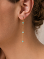 Close-up of a woman's ear wearing JaxKelly's Gemstone Chain Drop - Amazonite: a long 18k gold plated earring with three Amazonite beads spaced along a delicate chain. Her hair is pulled back against a neutral background.