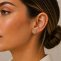 Close-up of a woman in profile with her hair in a low bun, wearing JaxKelly’s Round Amazonite Gemstone Gold Earrings—minimalist studs that stand out against her smooth, natural skin.