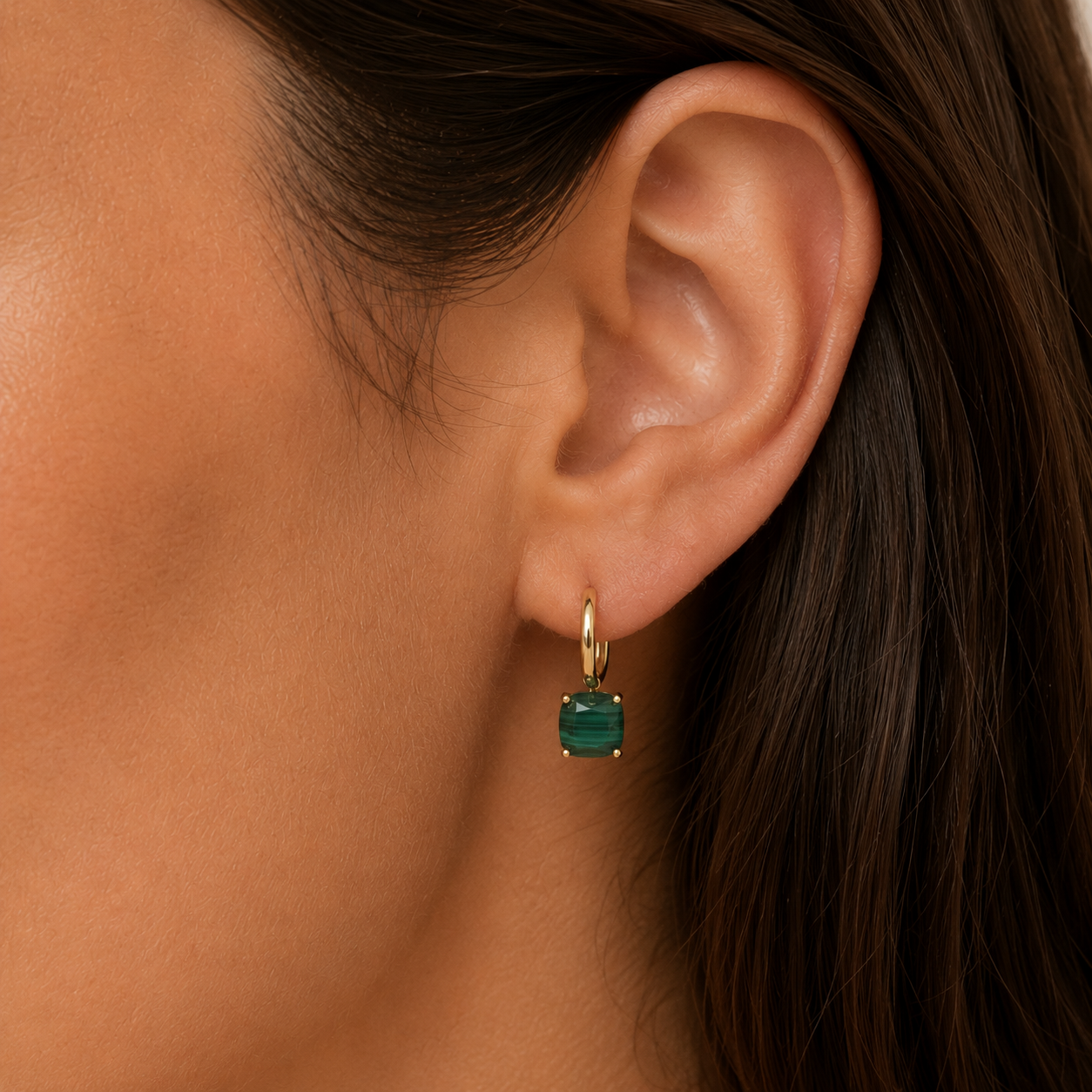 Close-up of a woman with long, dark brown hair and medium skin tone wearing JaxKelly's Gemstone Mini Drop - Malachite, tarnish-free gold plated hoop earrings featuring a cushion-cut malachite pendant.