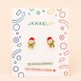 Two Elf Enamel Flat Back Kids Earrings by JaxKelly are displayed on a vibrant JaxKelly card labeled HYPOALLERGENIC and KID-FRIENDLY POSTS, with fun geometric patterns in the background—these charming earrings are beautifully crafted as gold plated earrings for sensitive ears.