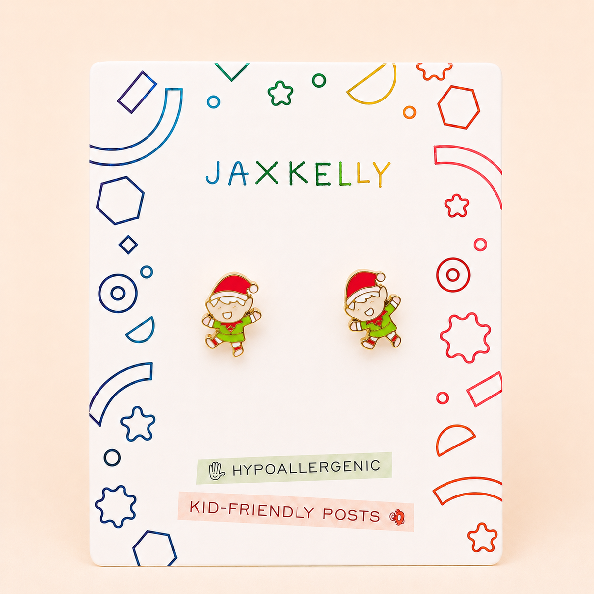 Two Elf Enamel Flat Back Kids Earrings by JaxKelly are displayed on a vibrant JaxKelly card labeled HYPOALLERGENIC and KID-FRIENDLY POSTS, with fun geometric patterns in the background—these charming earrings are beautifully crafted as gold plated earrings for sensitive ears.