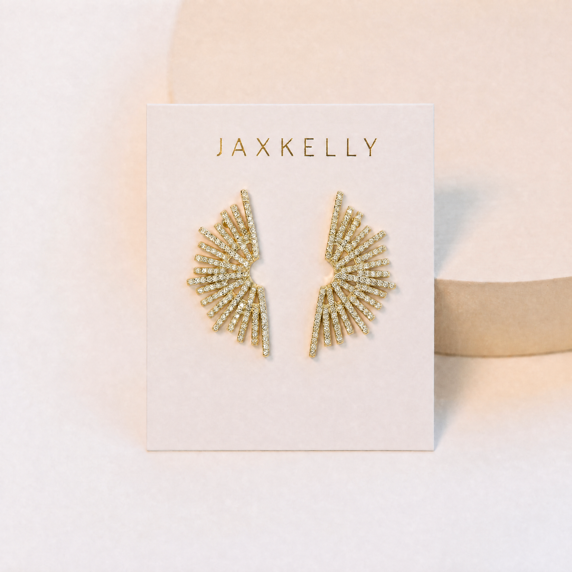 Sunburst Studs by JaxKelly feature gold vermeil with small pavé stones, shown on a white card with "JaxKelly" in gold lettering against a light, neutral background.