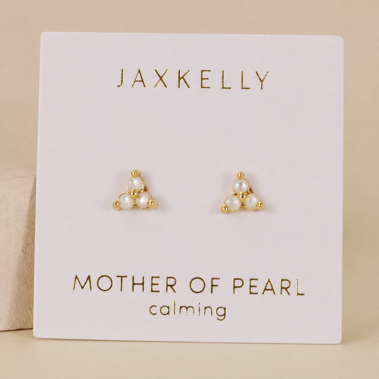 A pair of JaxKelly Trio Cluster Gold Earrings - Pearl featuring pearl-like beads and gold-plated accents, displayed on a white card.