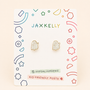 A pair of JaxKelly Ghost Enamel Flat Back Kids Earrings on a colorful card labeled kid-friendly posts, designed for sensitive ears, with abstract shapes decorating the border.