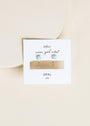 The Fire Opal Huggie: gold-plated earrings with lab-grown Fire Opal stones, shown on a white JaxKelly card labeled "wear good vibes" and "OPAL joy," against a light beige background.
