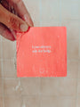 A hand holds a Teens Shower Affirmations™ card under running water. The waterproof red card, with “I can always ask for help” in white text and a smiley face, is ideal for sharing positive mindset quotes with teens.