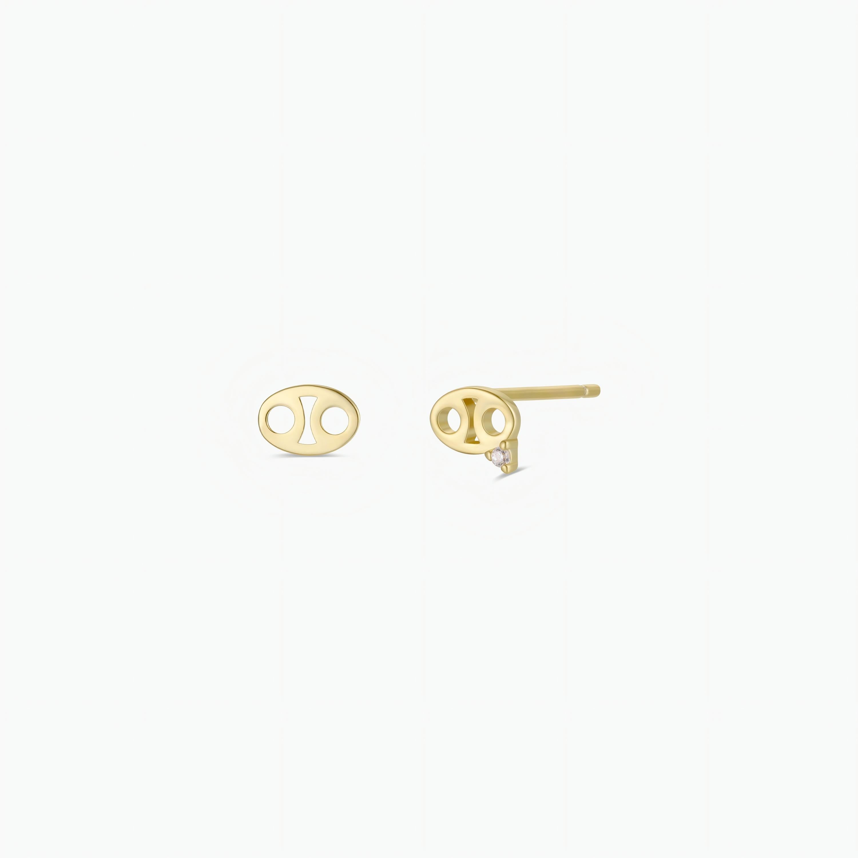 The Zodiac Earrings - Cancer are small, gold plated, oval-shaped studs. One earring is shown from the front with two circular holes, while the other displays the post and backing—ideal for ear piercings.