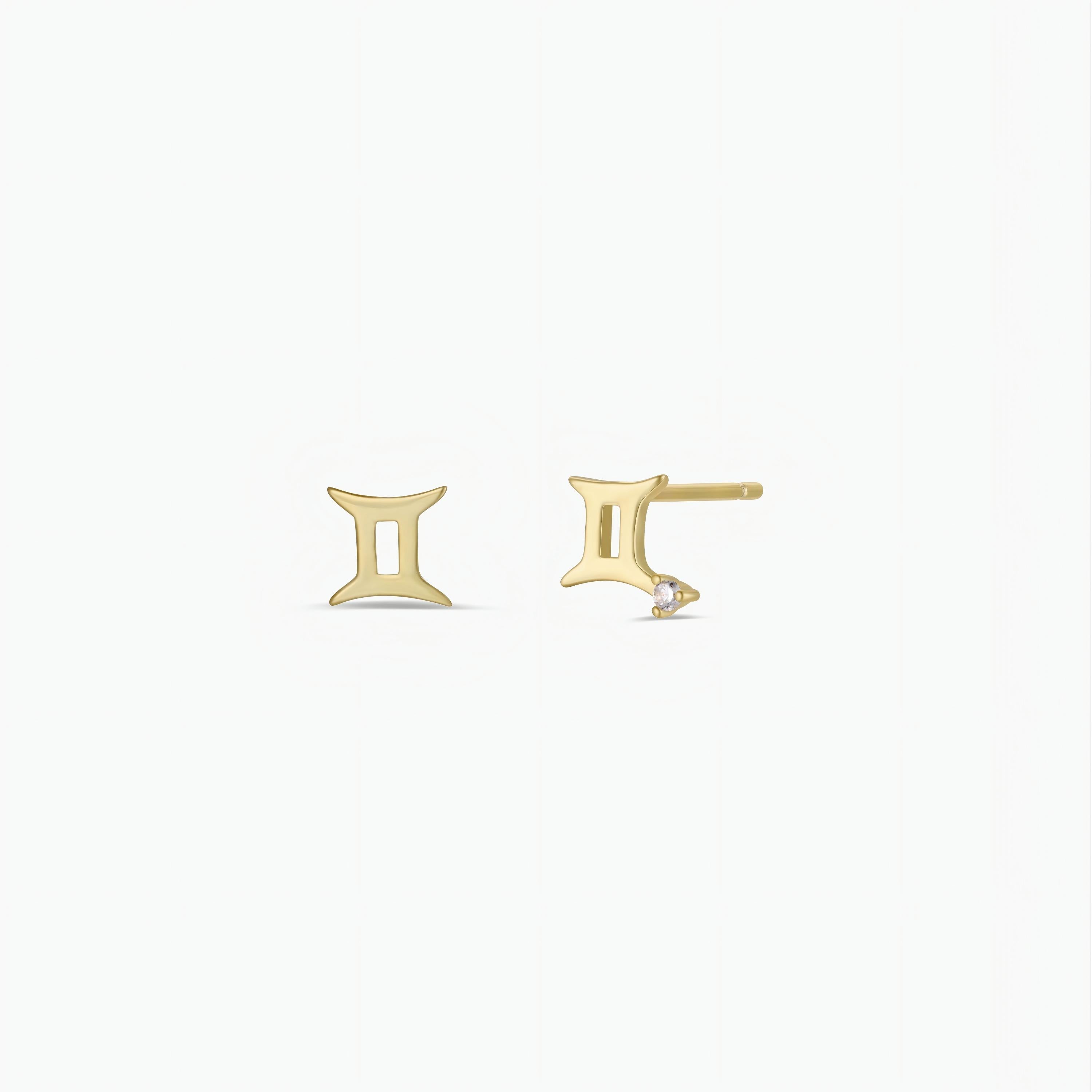 The Zodiac Earrings - Gemini feature a minimalist Gemini symbol in 18k gold plating with a clear gemstone at the base, subtly shining against a plain white background.