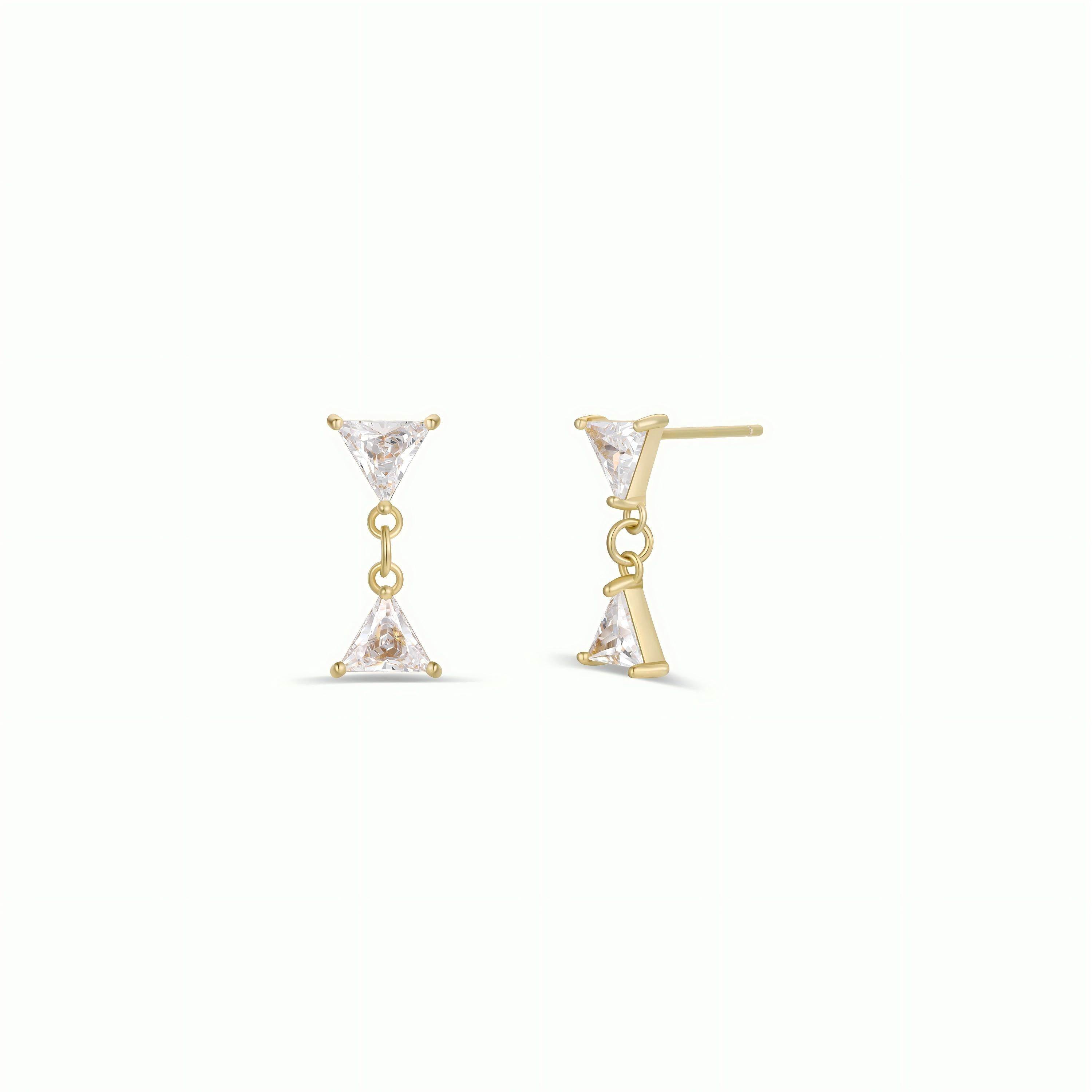 The Dual Triangle Drop features gold-plated earrings with two vertically aligned clear triangular CZ stones, joined by a small gold link and set on sterling silver posts, shown against a plain light background.