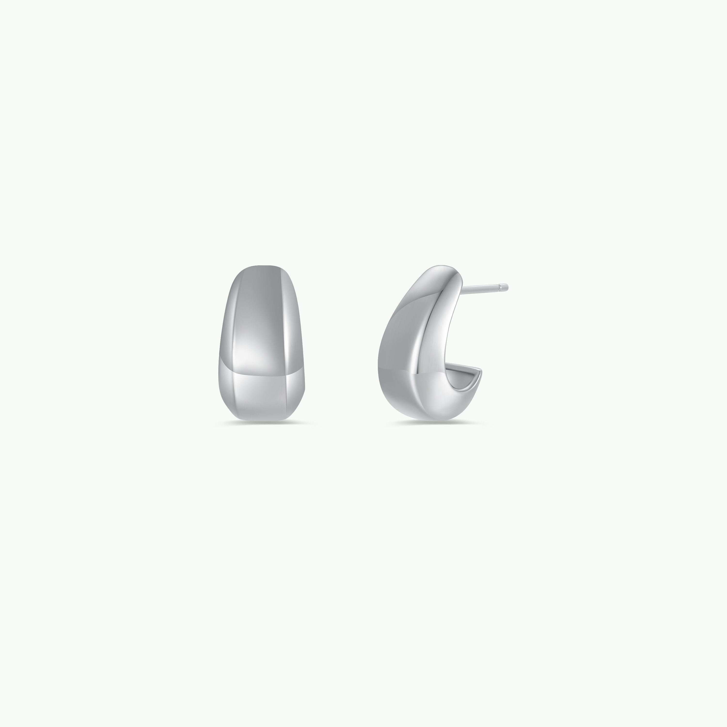 The Silver Bold Drop Earring, a pair of modern statement hoops, is displayed on a plain white background—one earring faces forward, while the other shows a side profile and sterling silver post.