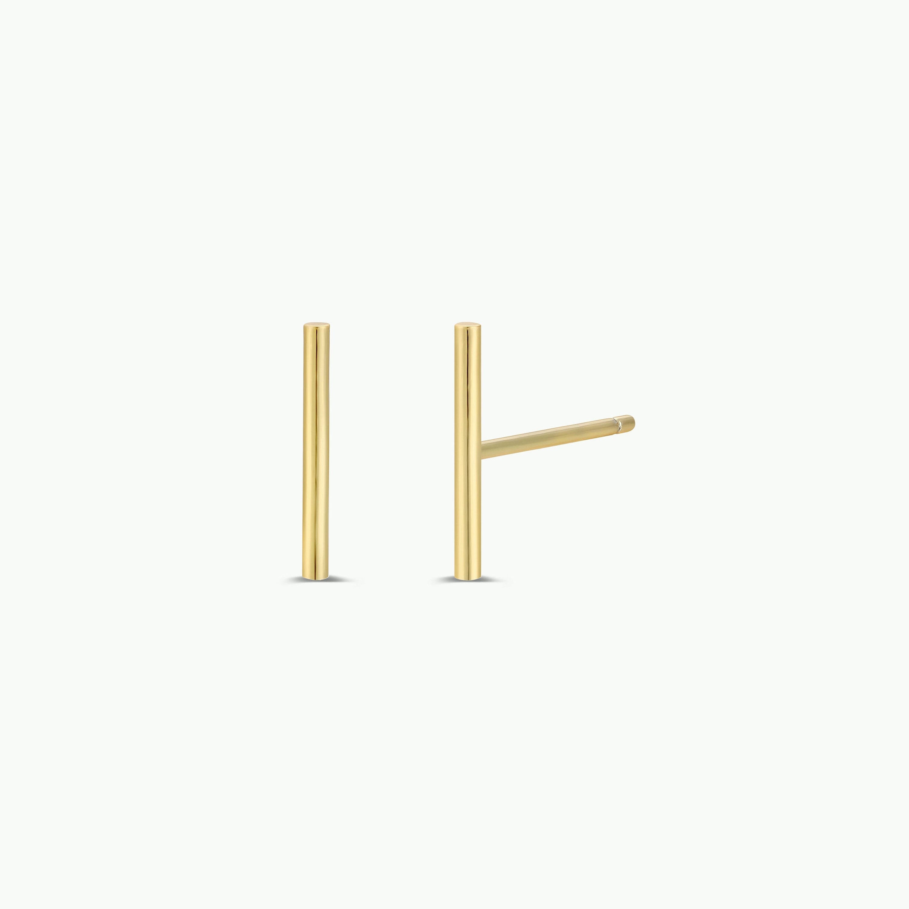 The Minimalist Bar earrings, featuring slim 18k gold plated bars with sterling silver studs, are displayed on a white background—one standing upright and the other angled to the right.