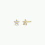 The Pavé Flower earrings are 18k gold plated star studs featuring small, round, clear gemstones on each point and sterling silver posts. These sparkling earrings stand out against a plain white background.