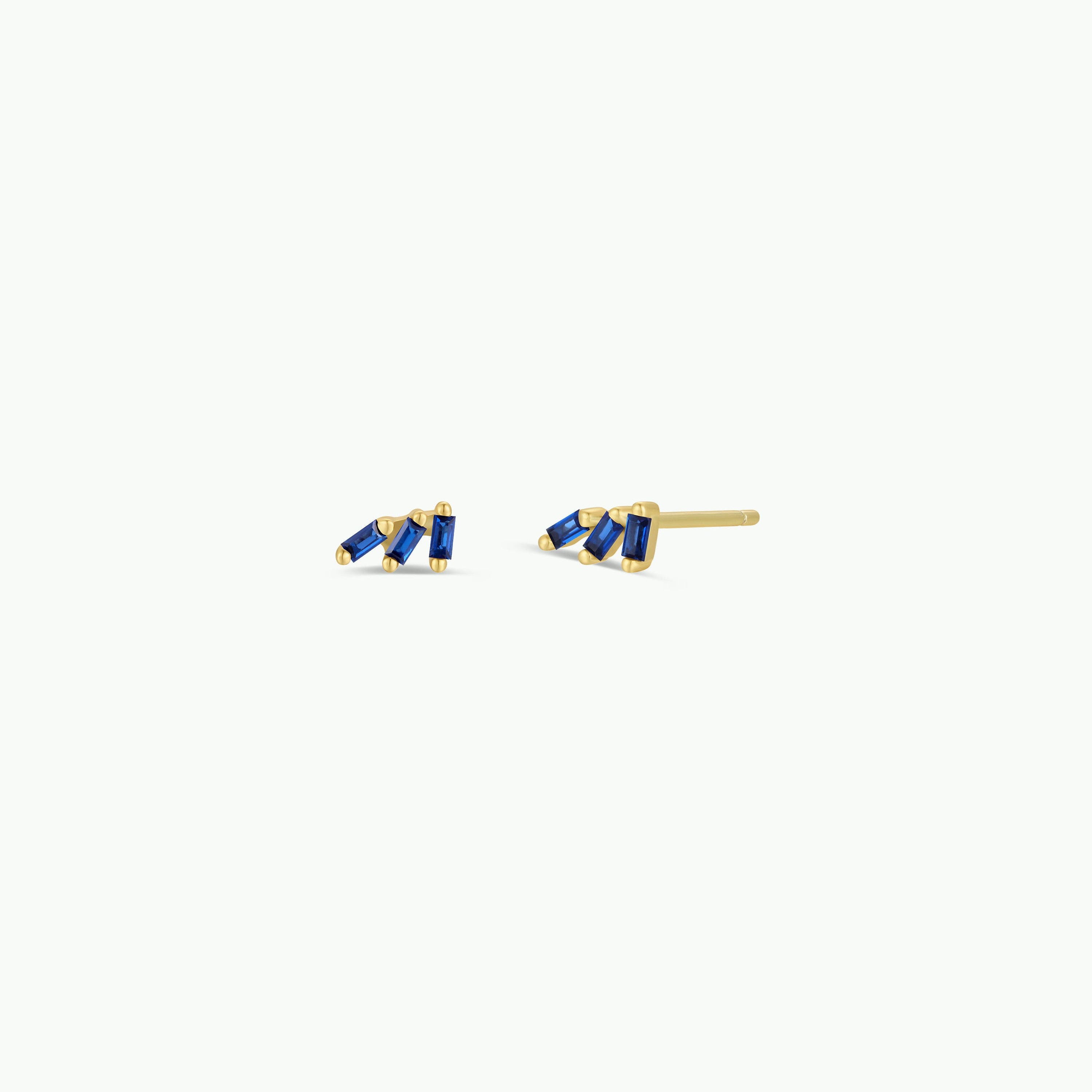 The Offset Trio - Sapphire earrings are gold plated studs, each with three rectangular sapphire CZ stones in a zigzag design, shown on a plain white background.