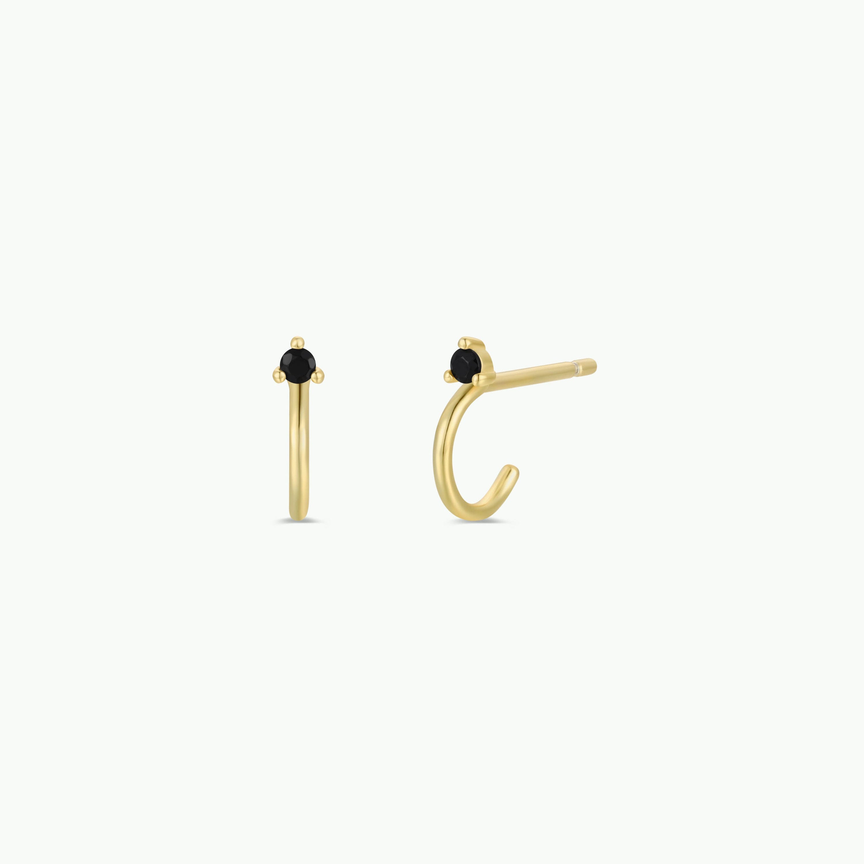 The Open Mini Hoop Earring - Black features a pair of small gold-plated nose rings with black CZ stones at the top, shown from front and side views on a white background. Their delicate hoop-inspired design adds an elegant touch.