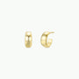 The Gold Wide Hoop earrings are small, chunky, and minimalist, shown on a white background—one hoop faces forward and the other sideways to reveal the post. Both feature elegant 18k gold plating.